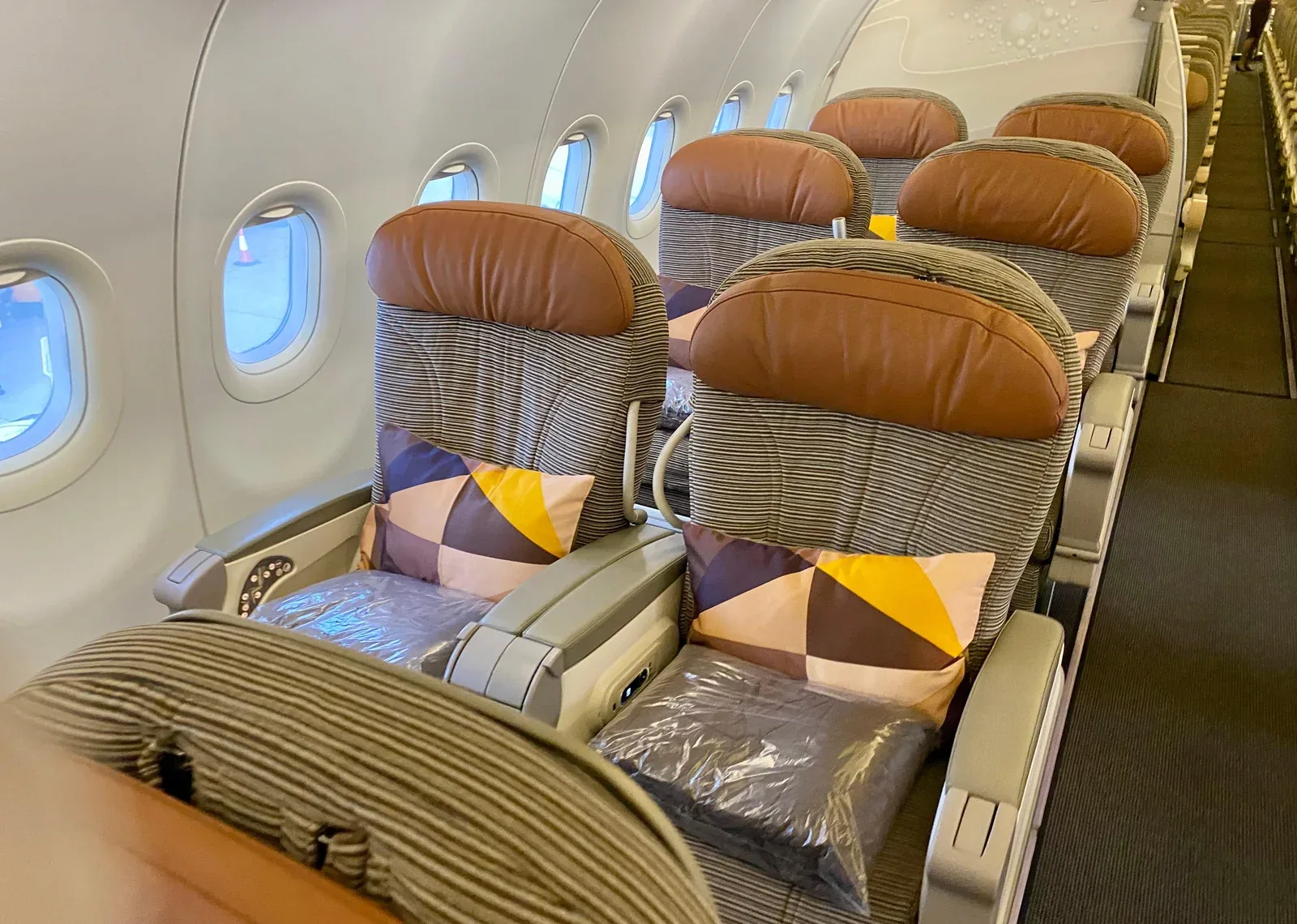 Ряд бизнес-класса Airbus A320 Etihad вдоль окон: широкие подлокотники и пледы в упаковке