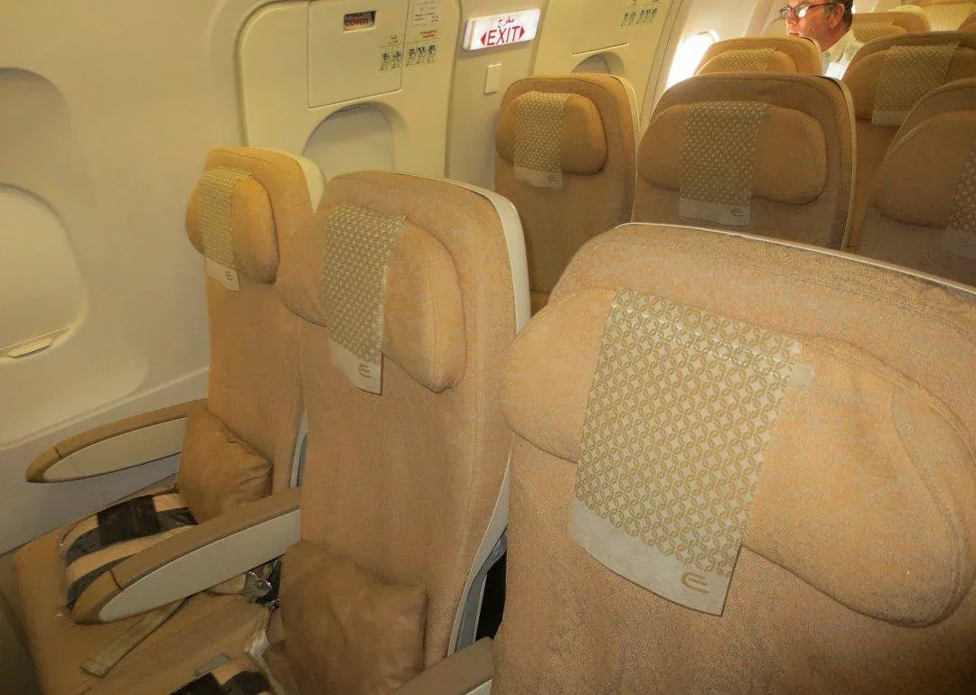 Ряд эконома Airbus A320 Etihad у аварийного выхода: створка, табличка EXIT и бежевые кресла с логотипом перевозчика