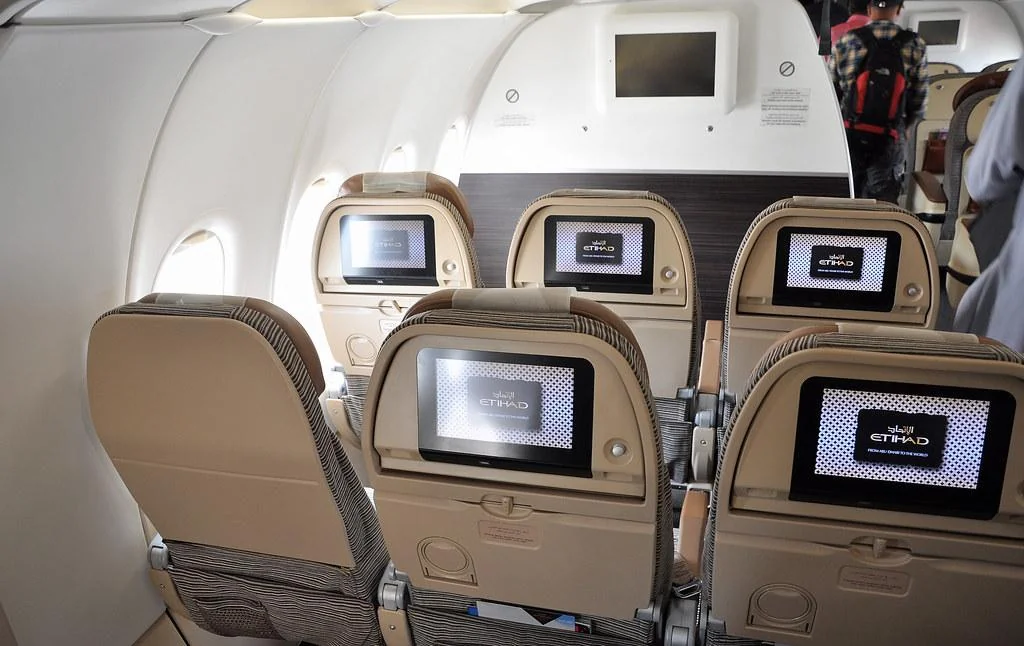 Первый ряд эконома Airbus A321 Etihad у перегородки: экраны в спинках и табло