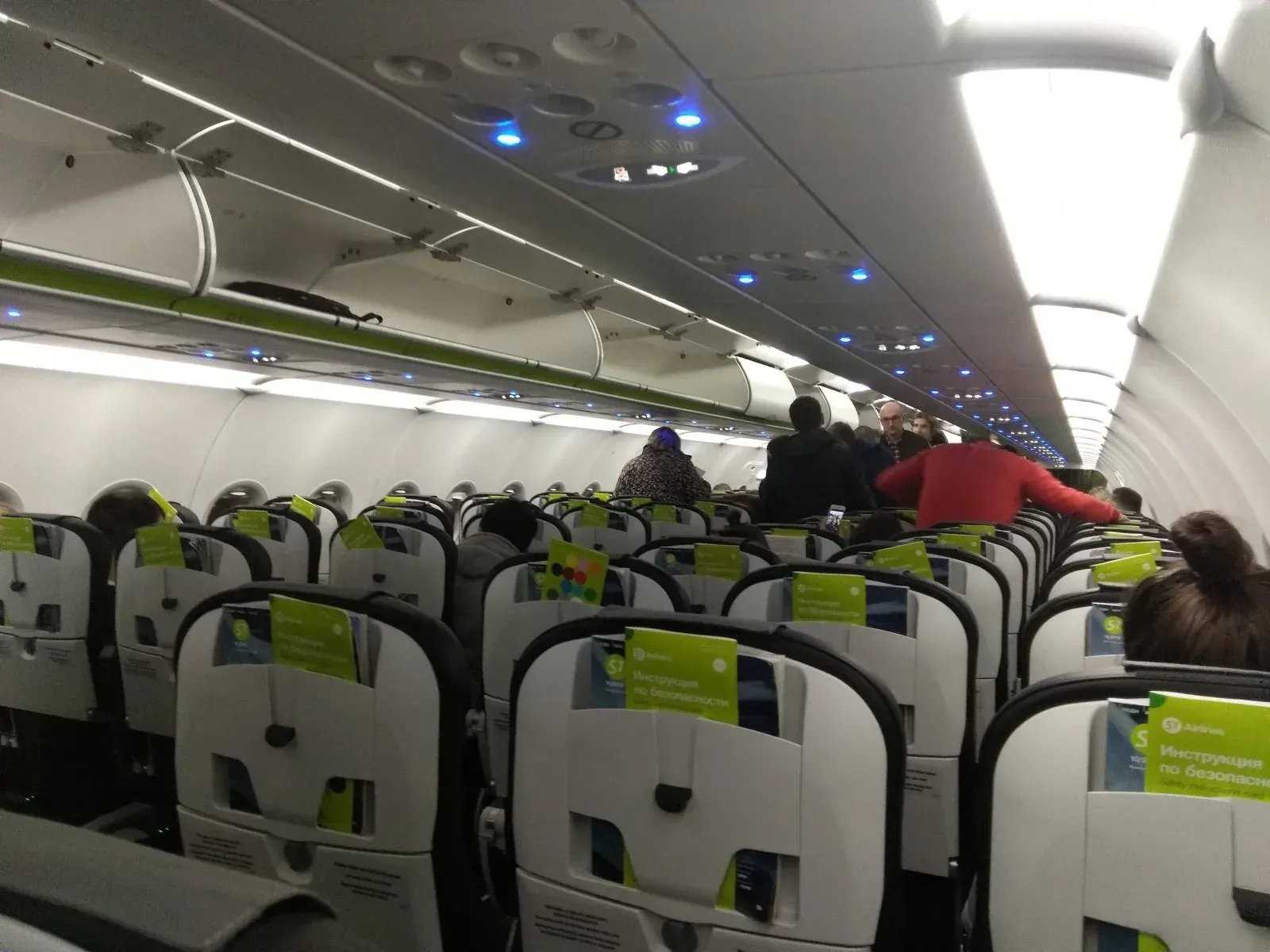 A321 S7 перед вылетом: пассажиры рассаживаются, горит синяя подсветка потолка
