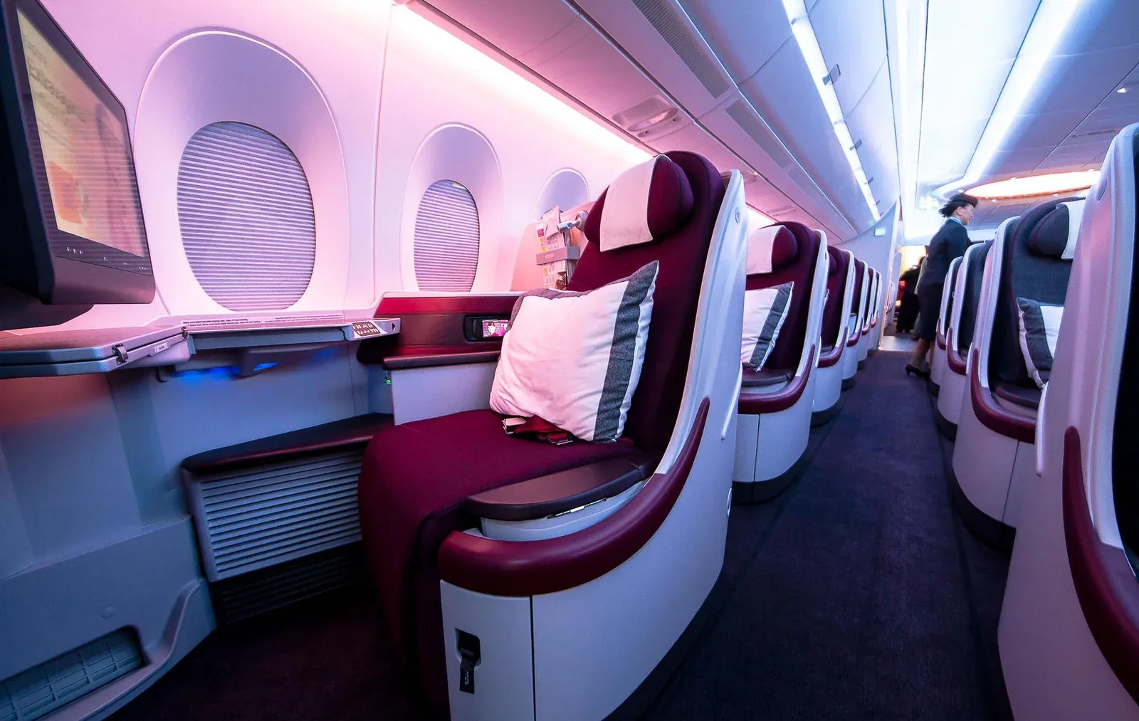 Открытый бизнес Airbus A350-900 Qatar Airways: кресло у окна с пледом и подушкой, вид вдоль прохода
