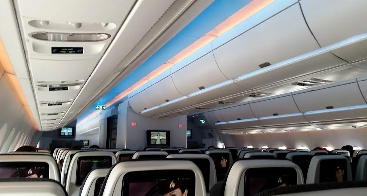 Салон эконома Airbus A350-900 Qatar Airways с включёнными экранами, вид вперёд