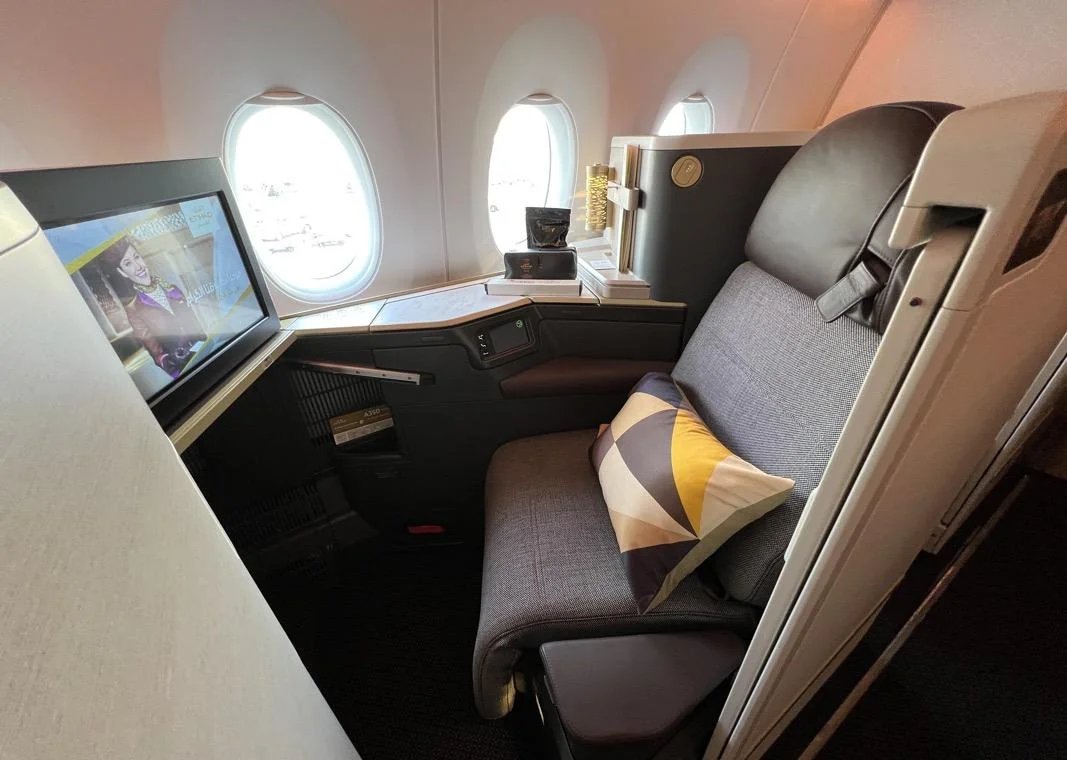 Кабина бизнес-класса Airbus A350 Etihad у окна: два иллюминатора и лампа на полке