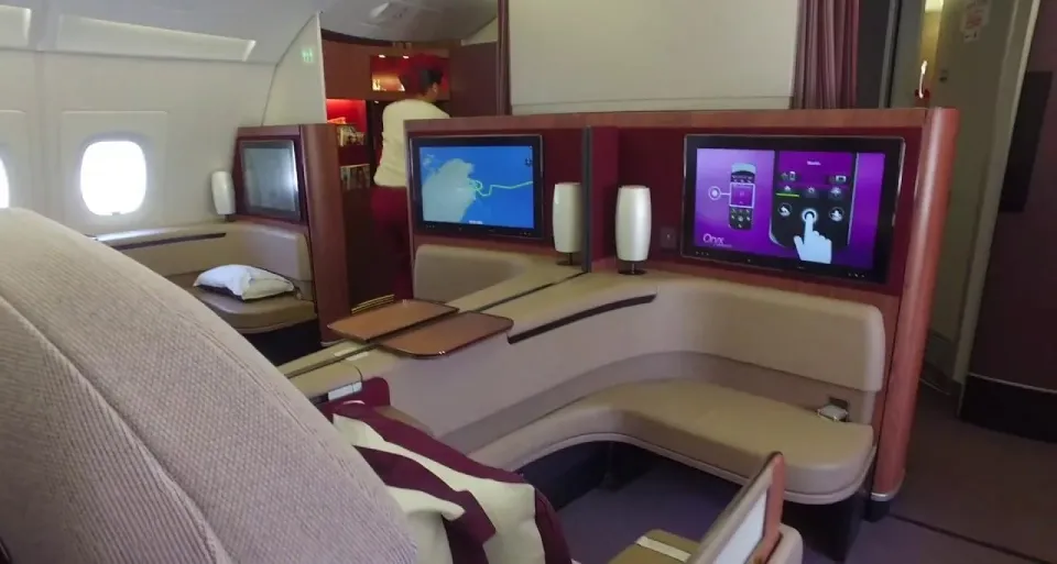 Два кресла первого класса A380 Qatar в центре с экранами и столиком