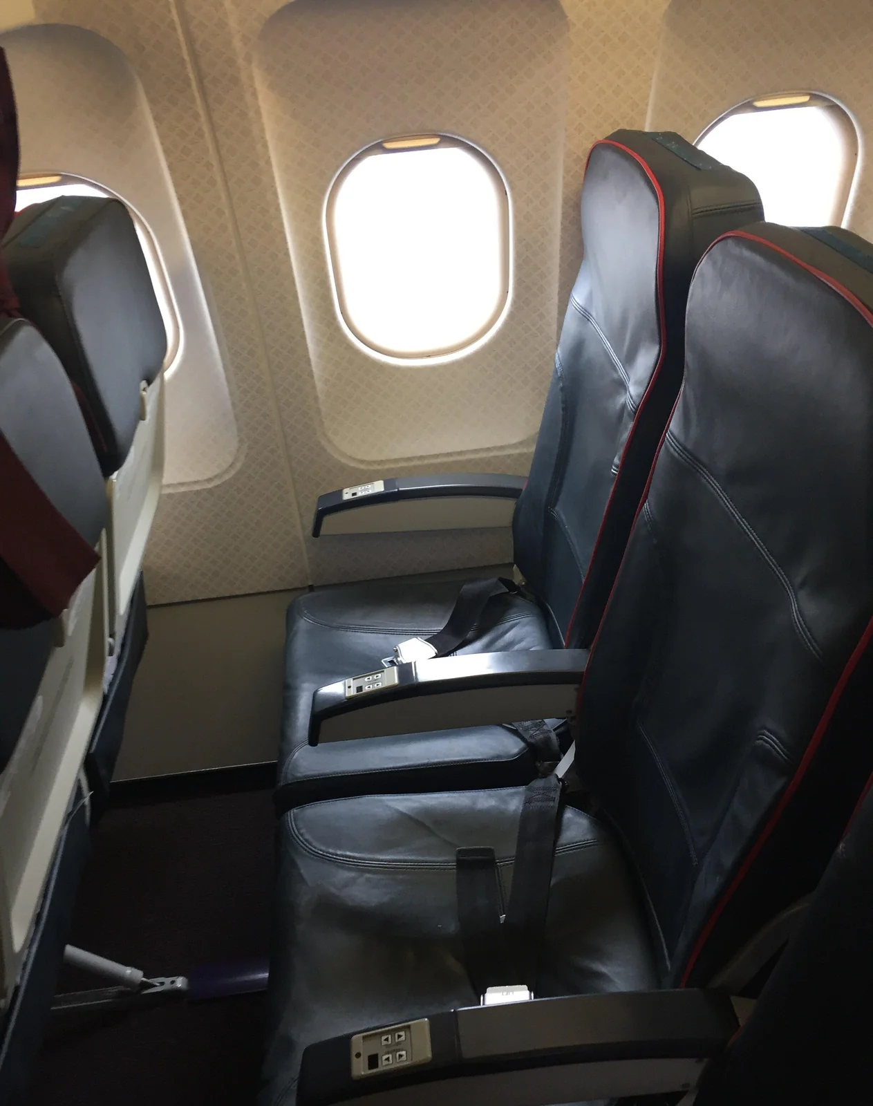 Кресла эконом-класса A319 «Уральских авиалиний» у иллюминатора: чёрная кожа с красным кантом