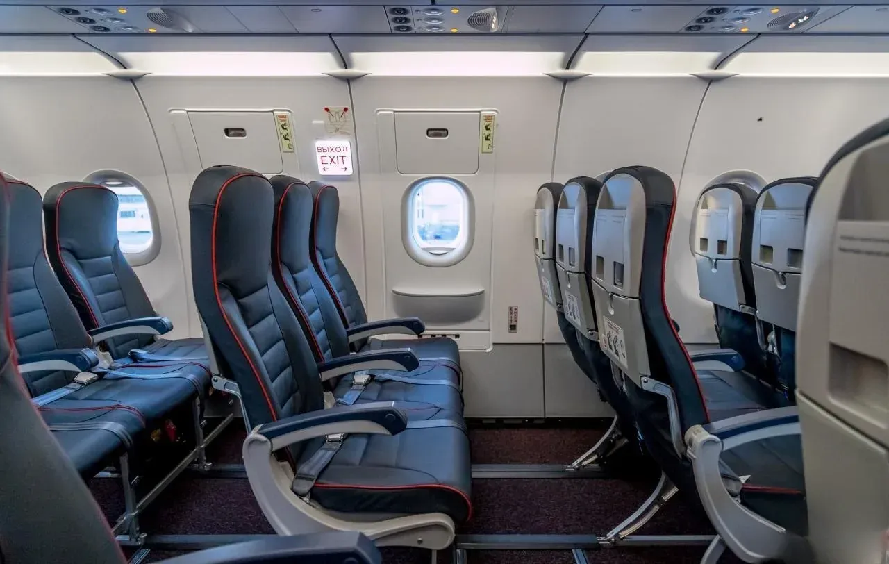 Ряд у аварийного выхода в Airbus A321 «Уральских авиалиний»: у борта вместо кресла проход к люку с табличкой «Выход»