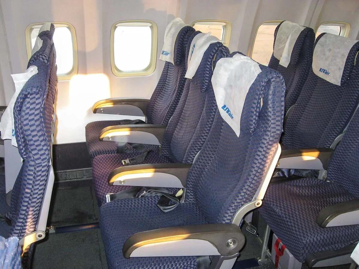 Кресла Boeing 737-500 ЮТэйр у иллюминатора с синей обивкой и фирменными накидками