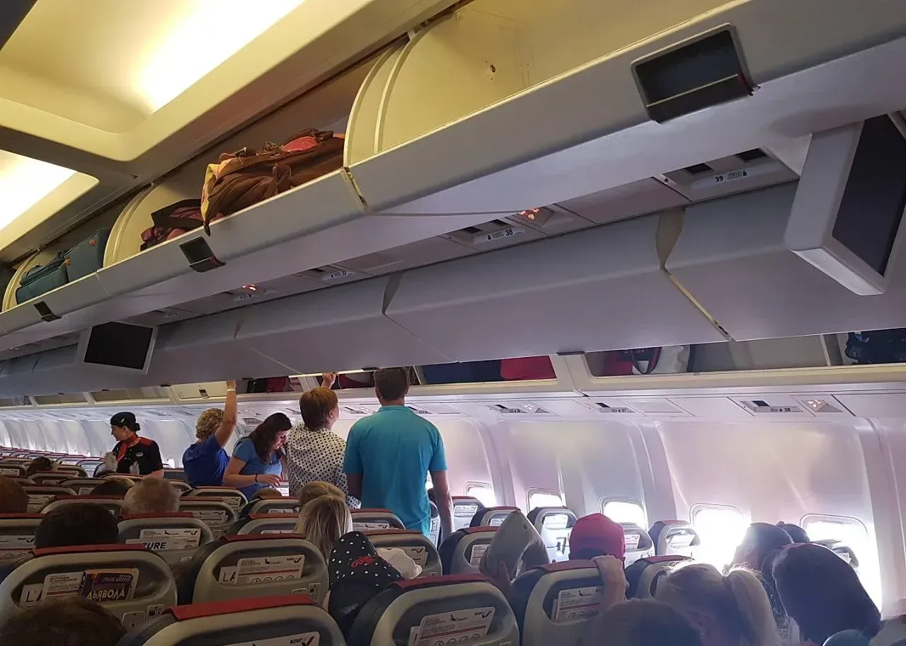 Проход и багажные полки в салоне Boeing 767-300 AZUR air во время посадки
