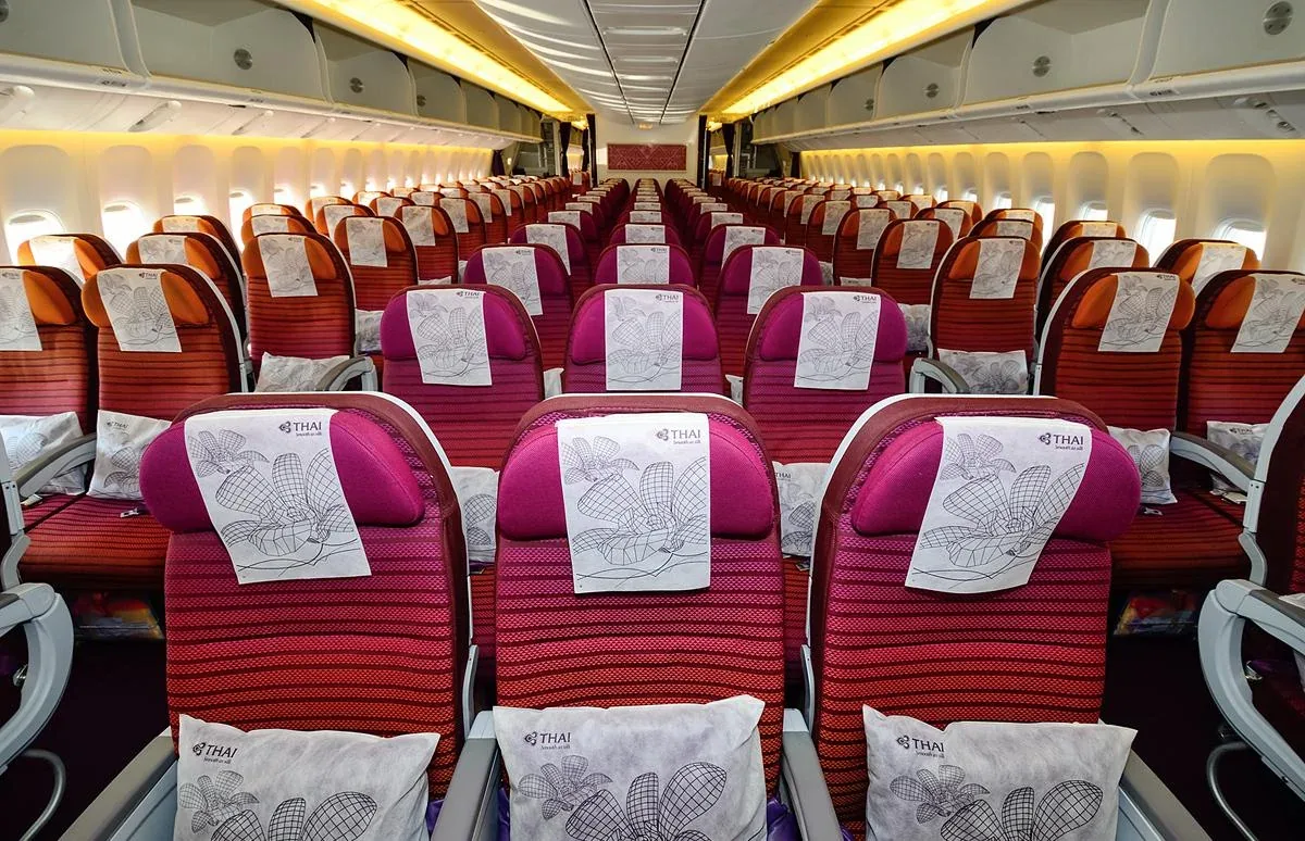 Салон эконома 777-300ER Thai Airways с малиновыми креслами