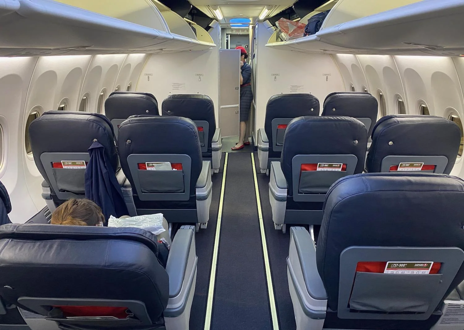 Эконом-класс Boeing 737-900ER Turkish Airlines: синие кресла и бортпроводник в проходе
