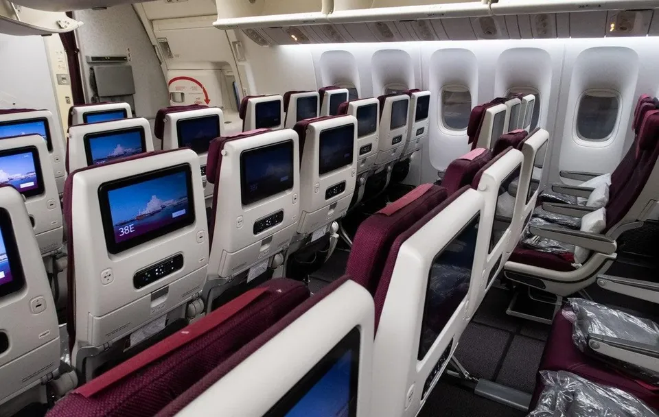 Кресла эконома 777-300ER Qatar Airways у окон, экраны и бордовые подголовники