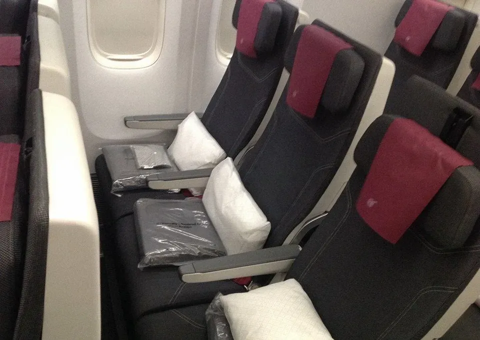 Тройка кресел эконома у окна Boeing 777-300ER с подушками и пледами
