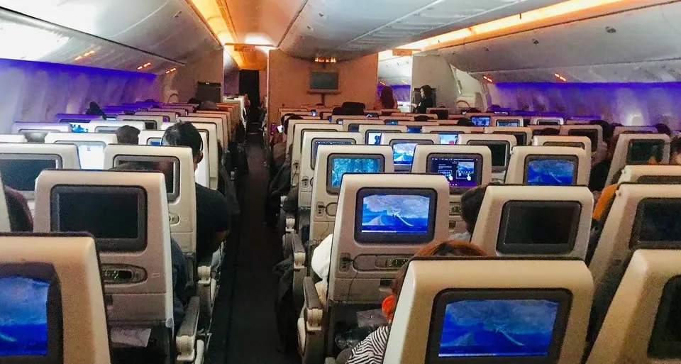 Салон эконома 777-300ER Qatar Airways в вечерней подсветке, экраны включены