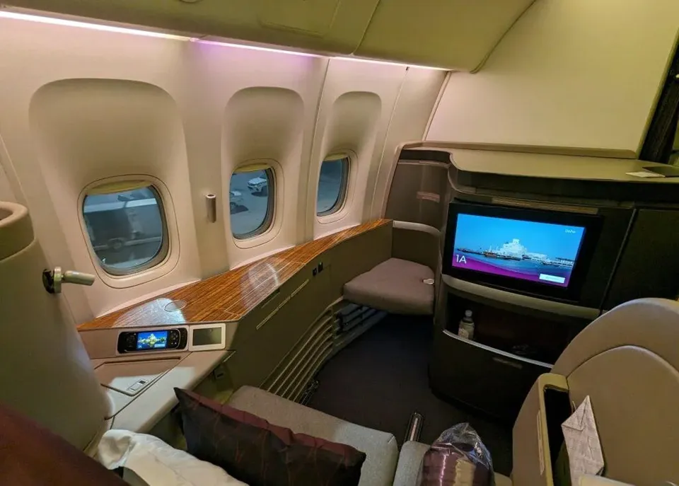 Кресло 1A первого класса Boeing 777-300ER Qatar Airways: три окна, деревянная консоль и большой экран