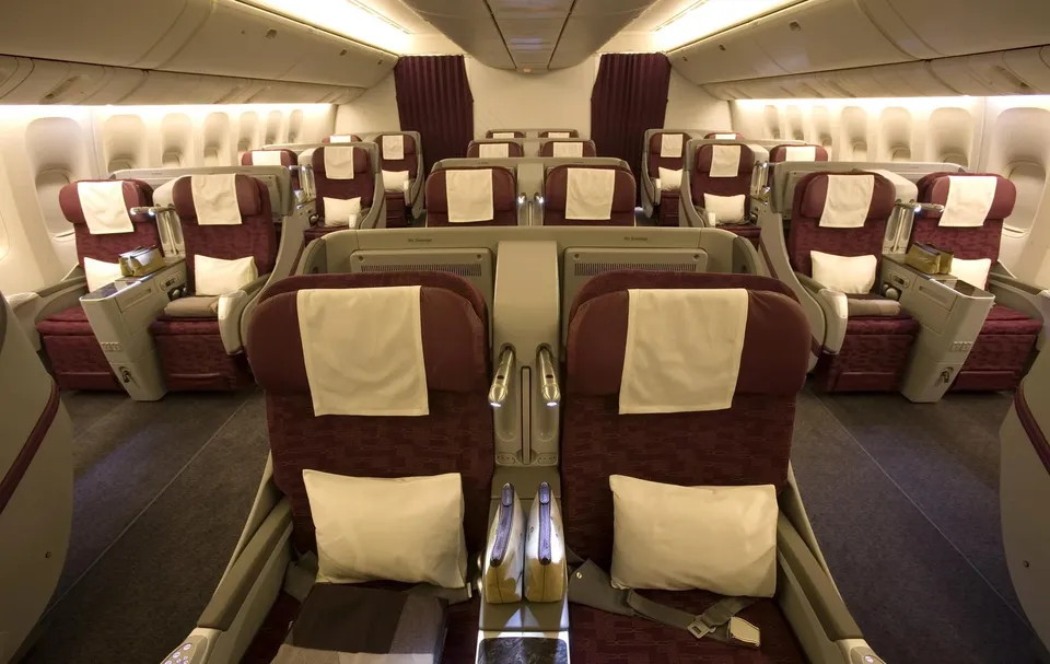 Бизнес 2-2-2 на 777-300ER Qatar Airways: пары бордовых кресел с подушками
