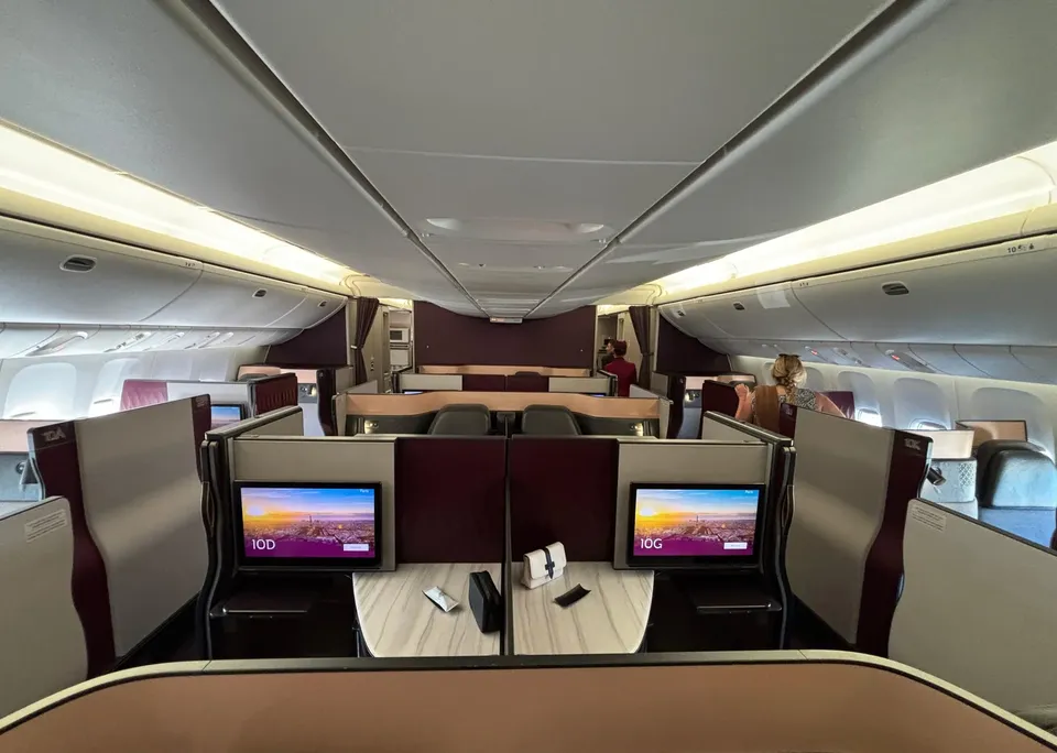 Центральные кабины Qsuite на Boeing 777-300ER Qatar Airways с общим столом и двумя экранами
