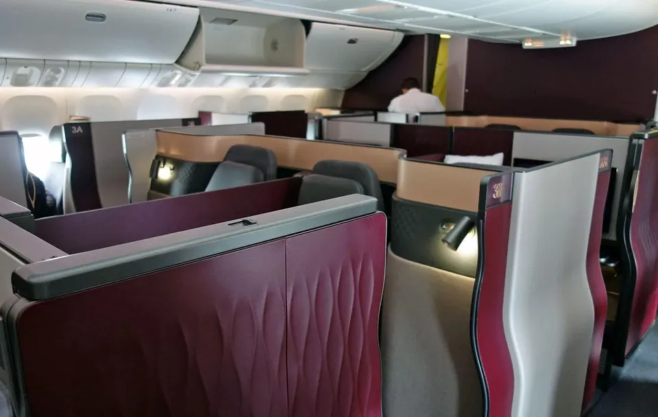 Салон Qsuite 777-300ER Qatar Airways: кабины с бордовыми перегородками вдоль прохода