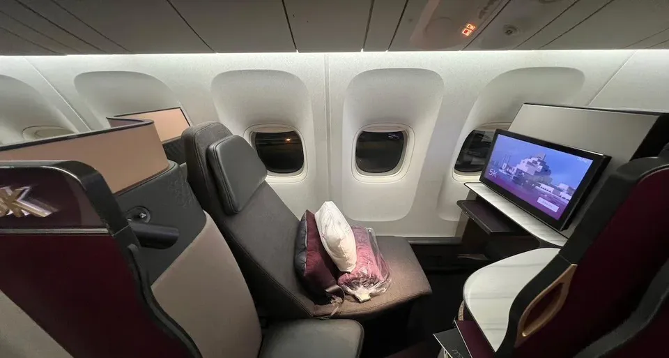Кабина Qsuite у окна Boeing 777-300ER: кресло, экран и подушка