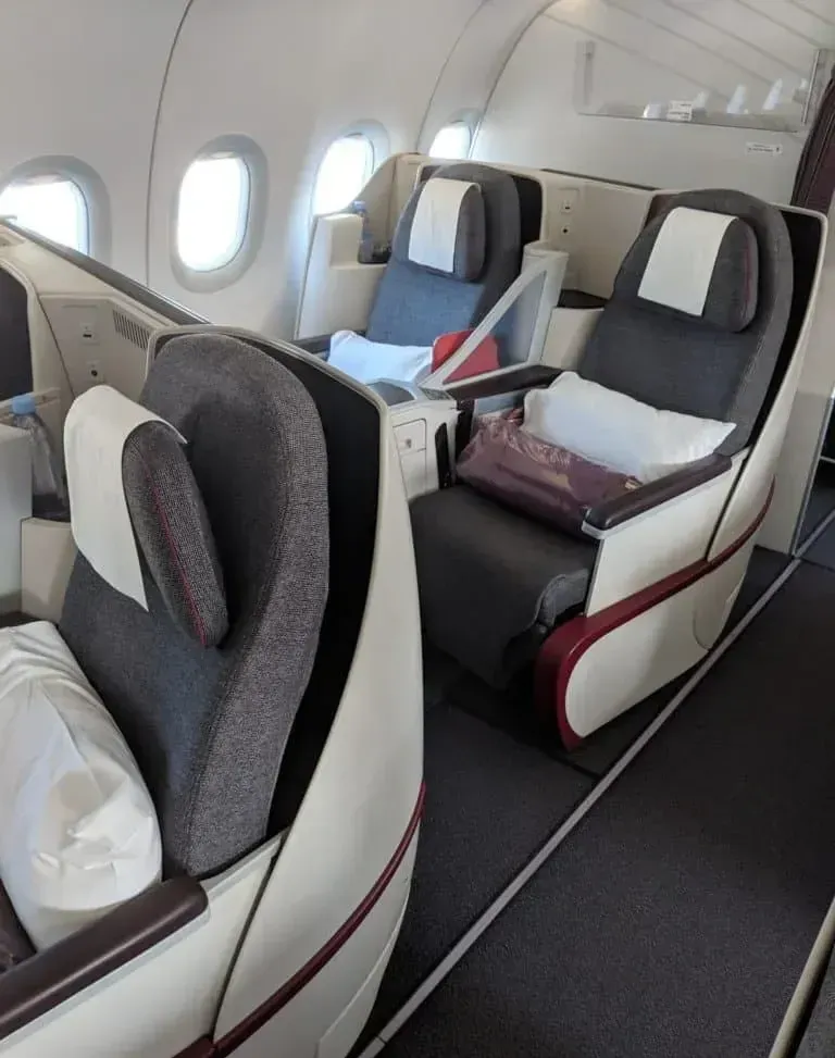 Пара кресел бизнеса Qatar Airways у окон, вид из прохода