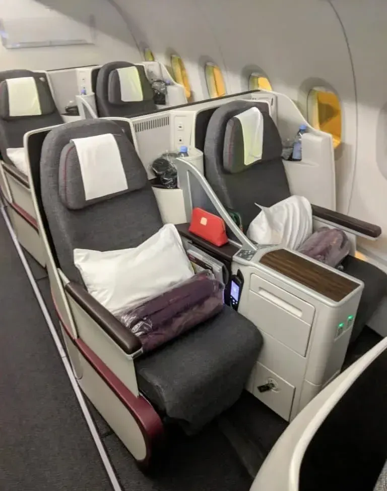 Кресла бизнеса Qatar Airways у стенки салона со столиком между местами