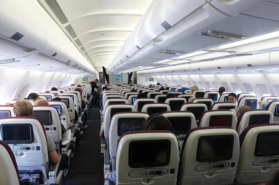 Салон эконома Qatar Airways в полёте, экраны в каждой спинке