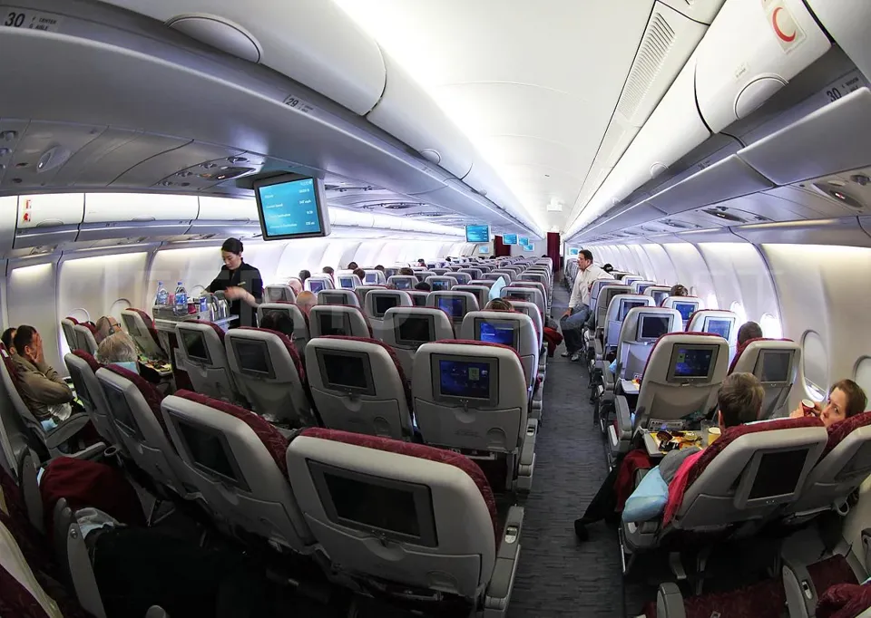 Салон эконома A330-300 Qatar Airways в полёте, экраны в спинках